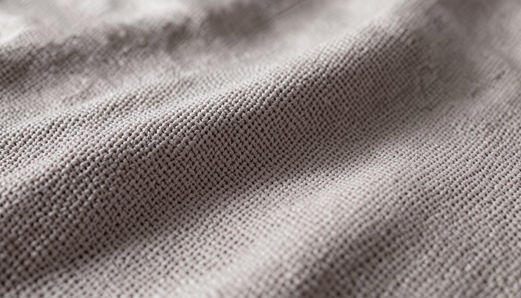 Tecido cinzento entrelaçado em grande plano, textura densa e uniforme, tons neutros e sóbrios.