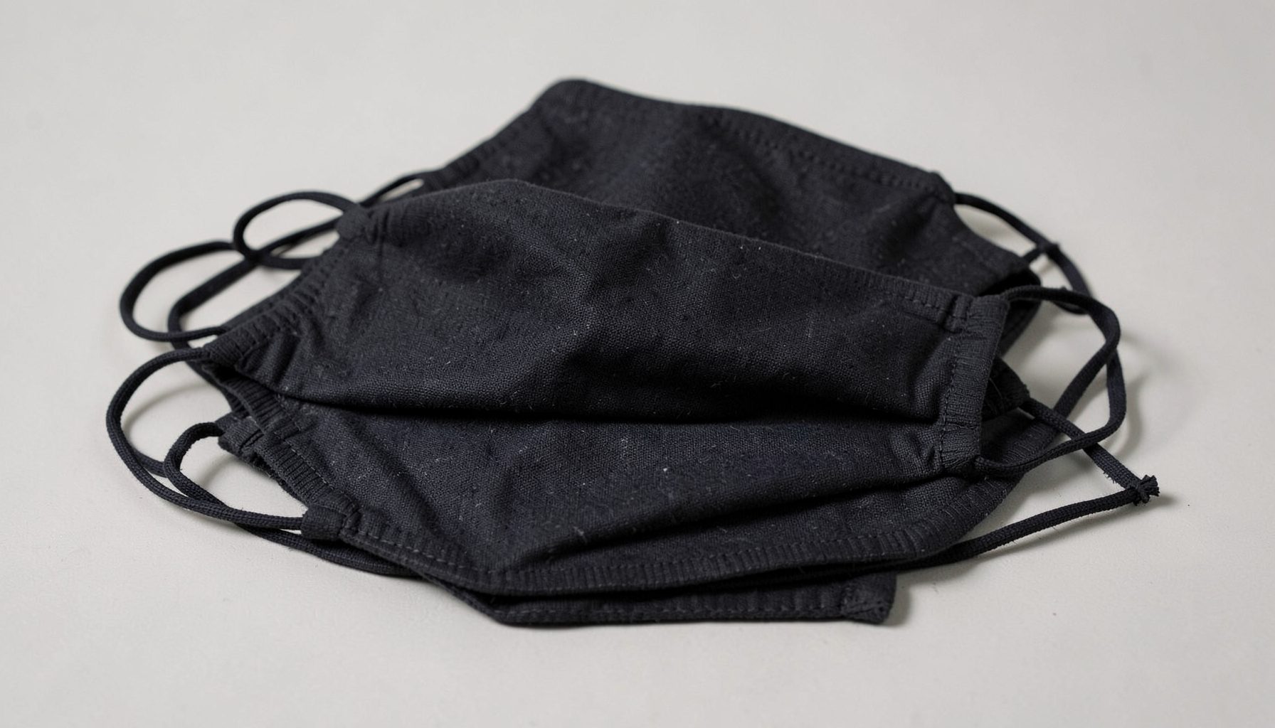 Pilha de máscaras faciais pretas com elásticos, sobre fundo claro